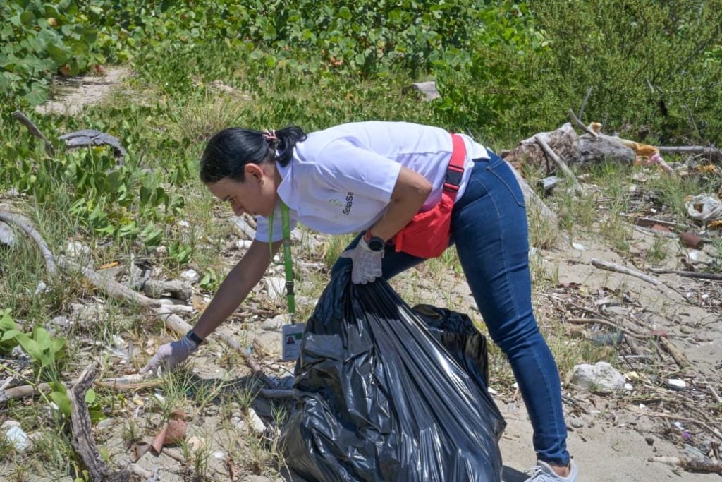 Colaboradora de SeNaSa limpiando las playas